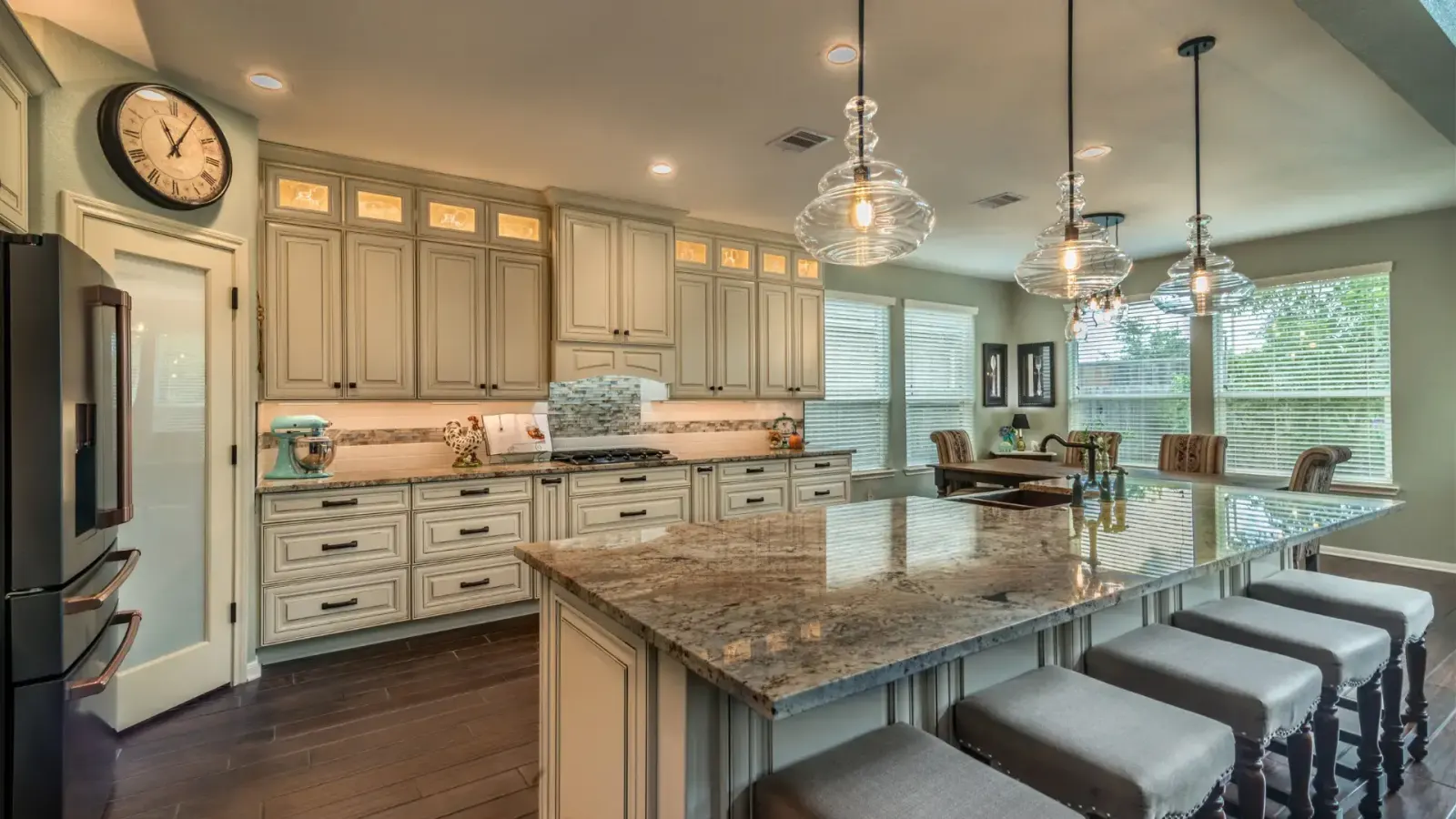 Remodeled kitchen with white cabinets, island seating, and pendant lighting
